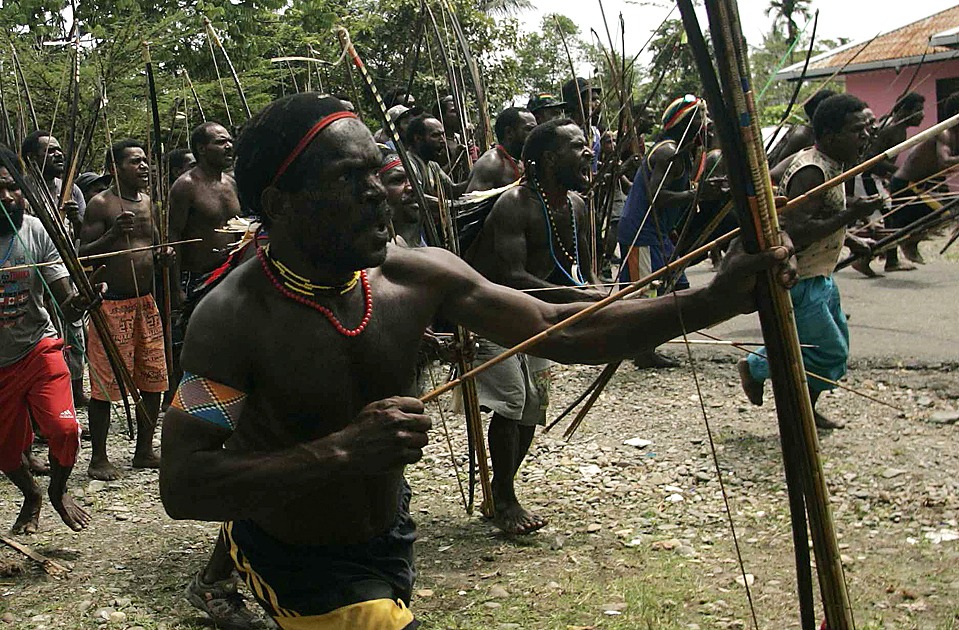 Dani tribesmen hold their weapons as they attack the Damal tribe during intertribal wars in the village of Old Kwaki in Timika